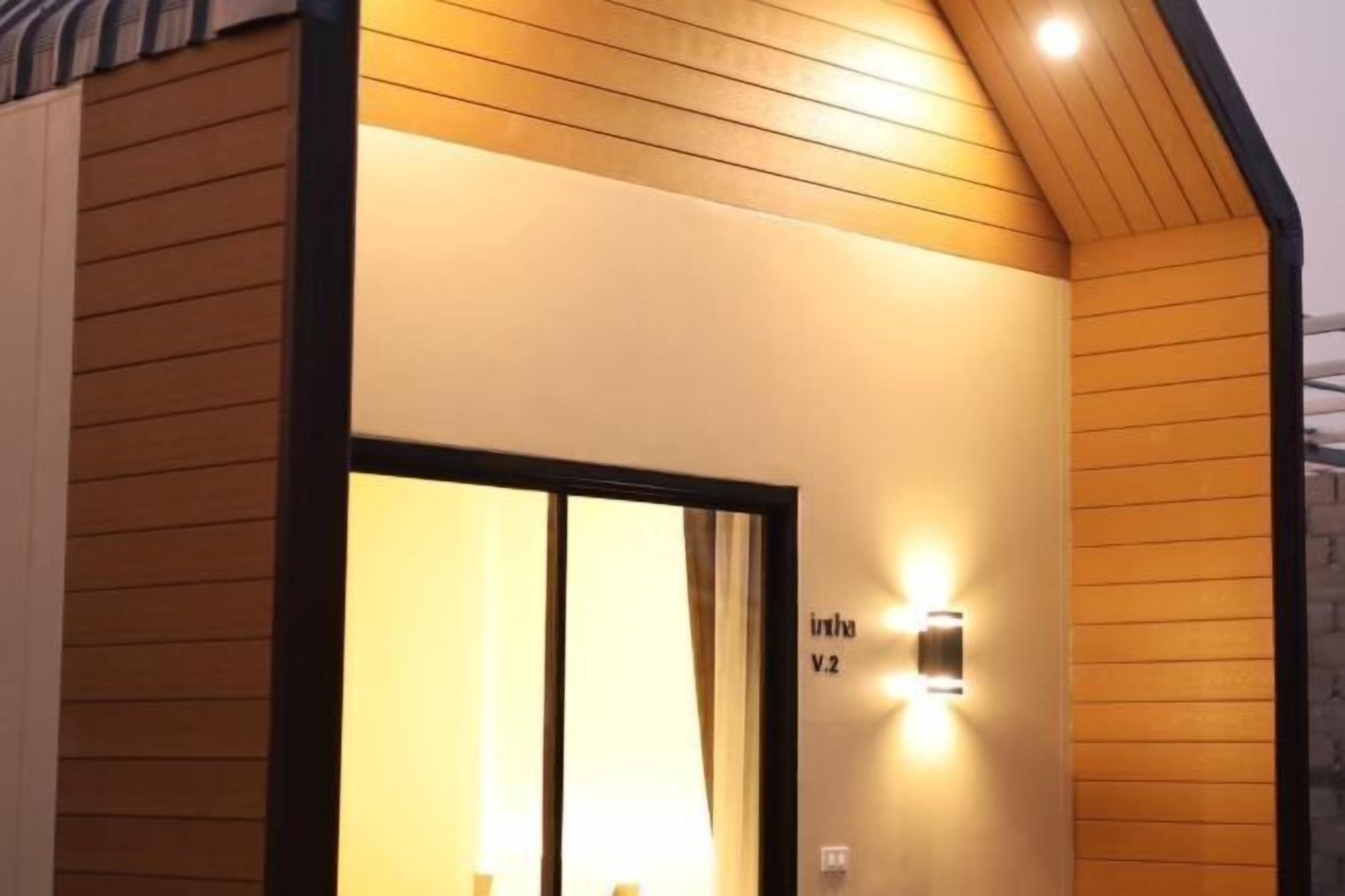 A hotel entrance with a wooden facade, a glass door, and a wall-mounted light fixture.