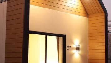 A hotel entrance with a wooden facade, a glass door, and a wall-mounted light fixture.