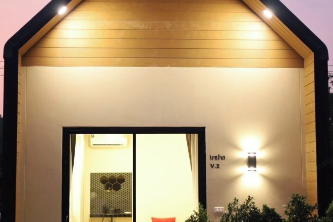 A modern building with a sloped roof, a large entrance with glass doors, and a wall-mounted light fixture.