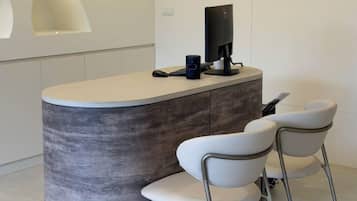Een receptiegedeelte met een gebogen balie, een flatscreen-televisie, een koffieapparaat en twee witte stoelen.