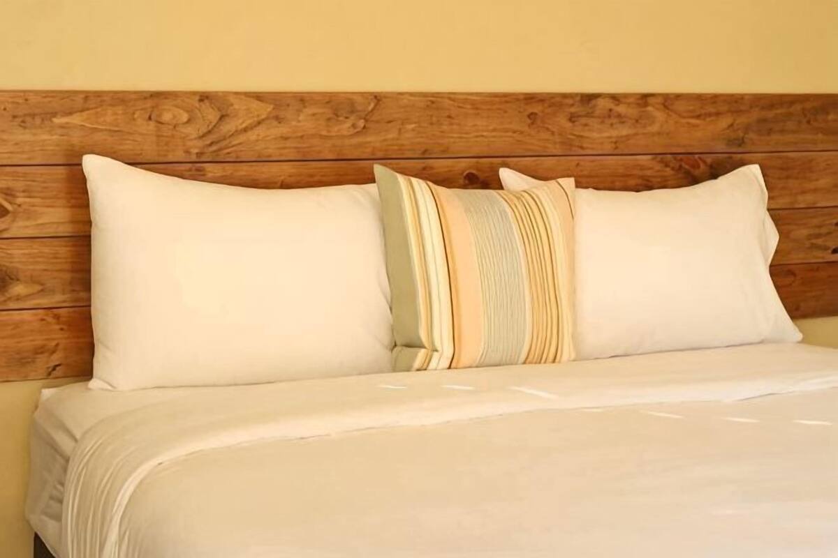 A bed with a wooden headboard, two pillows, and a beige bedspread.