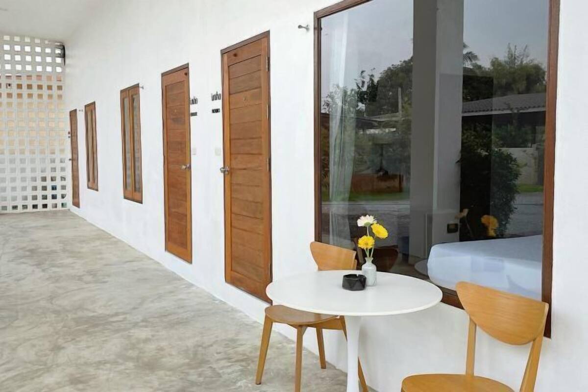 A modern room with a white wall, wooden doors, and a round table with chairs.
