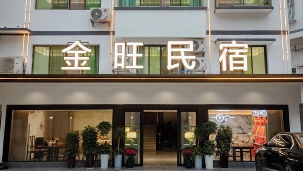 Een hotel met een moderne gevel, grote ramen en een uitnodigende entree met plantenpotten.