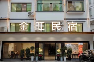 Un hotel con una fachada moderna, grandes ventanales y una entrada acogedora con plantas en macetas.