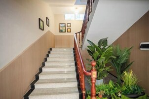 Una escalera con barandales y pasamanos de madera que lleva a un rellano con cuadros en la pared.