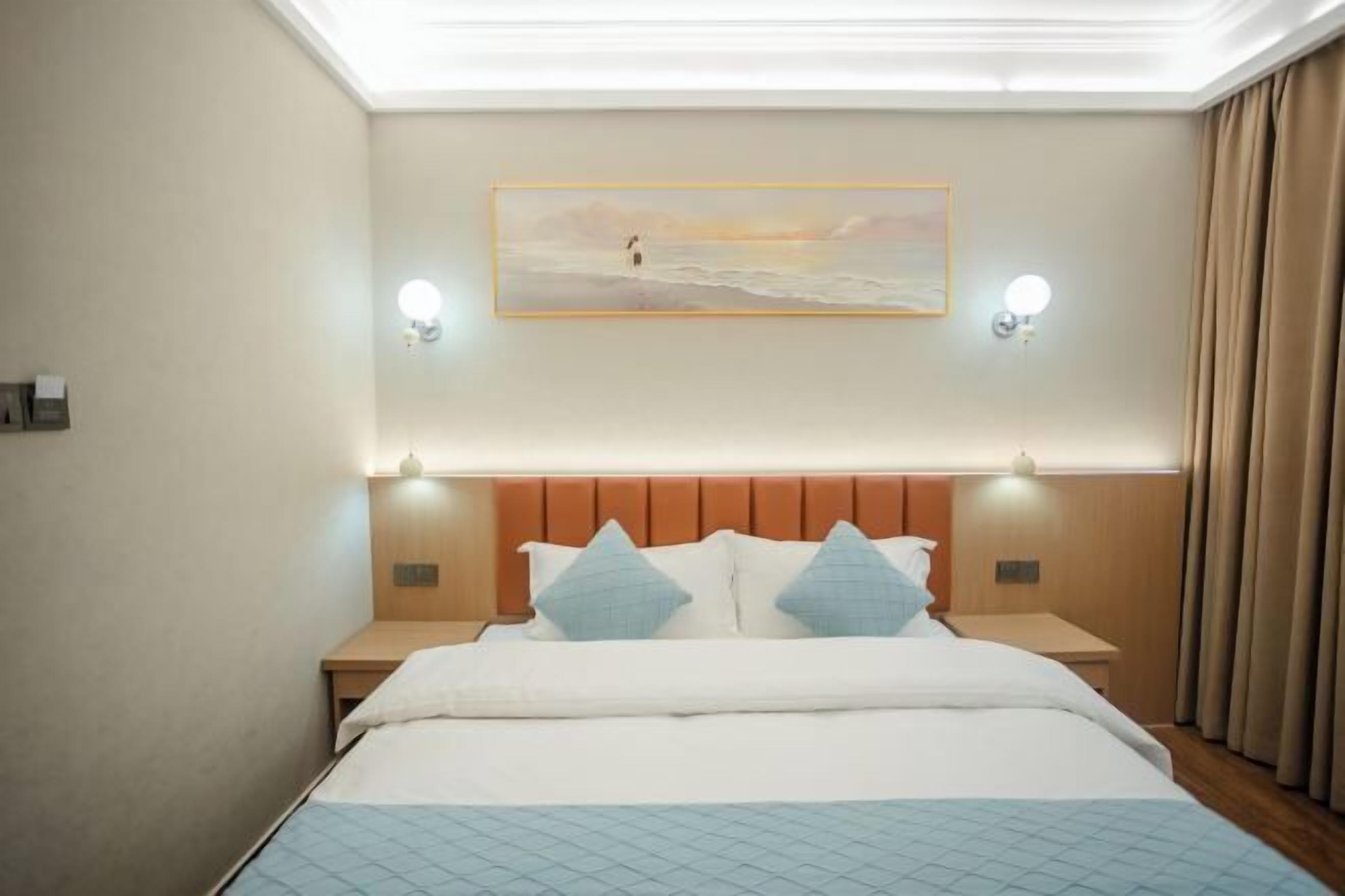 A hotel room with a bed, nightstands, a painting on the wall, and a view of the sea.
