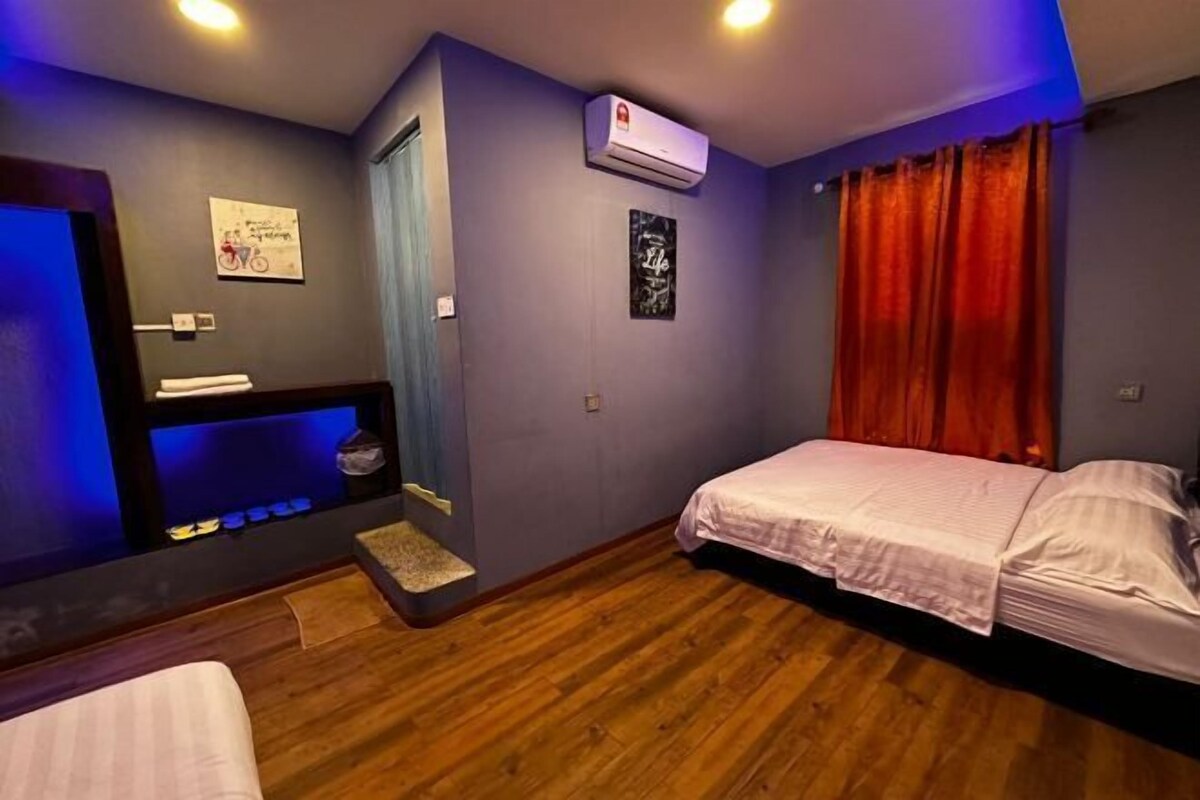 A bedroom with a bed, a small desk, a mirror, an air conditioner, and a window with curtains.