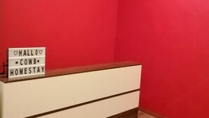 A reception desk with a sign that reads "HALLO COWB HOMESTAY" against a red wall. - Cow B Homestay Semporna (Semporna)