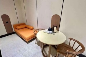 A small room with a single bed, a round table with chairs, and a wall-mounted shelf. - Urban Inn, Serai Wangi (Padang Serai)