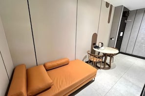 Quarto moderno com sofá, mesa redonda pequena e cadeiras.