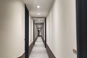 A long, narrow hotel corridor with a carpeted floor and a series of doors on one side. - Urban Inn, Serai Wangi (Padang Serai)