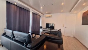 A modern living room with a sofa, a coffee table, and a flat-screen TV. - Spacious 2BR Boracay Luxury Condo (Boracay Island)