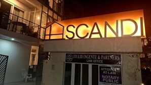 A building with a lit-up sign reading "SCANDI" and a sign for "Itulid Ingente & Partners Law Office" below it. - Spacious 2BR Boracay Luxury Condo (Boracay Island)