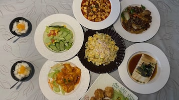 A table with various dishes including a bowl of soup, fried rice, and several plates of food.