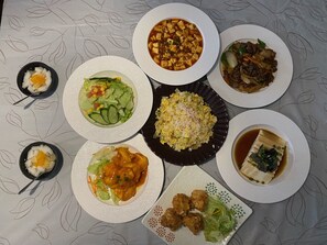 A table with various dishes including a bowl of soup, fried rice, and several plates of food.
