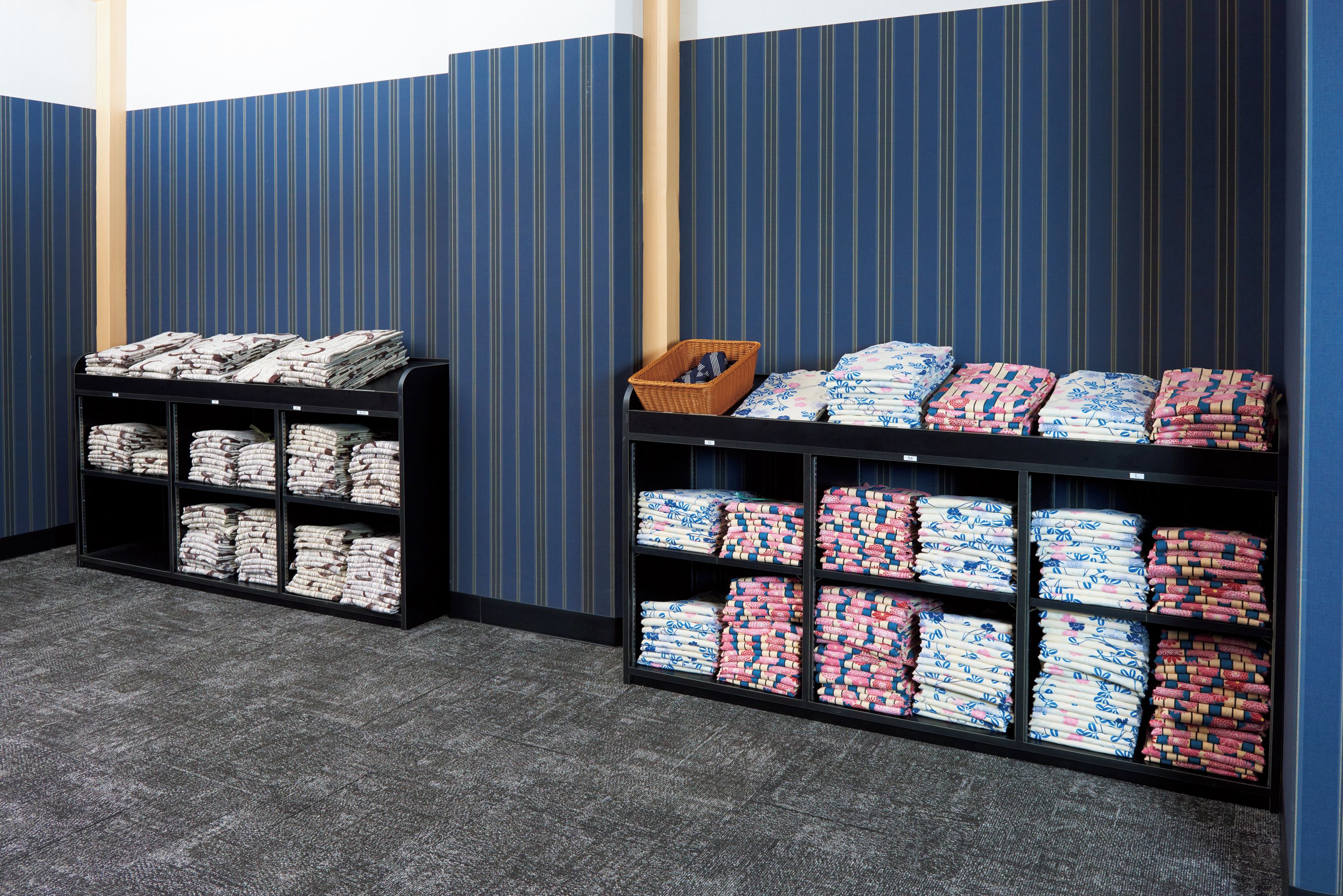 Una habitación con dos estanterías negras repletas de ropa de cama bien doblada.