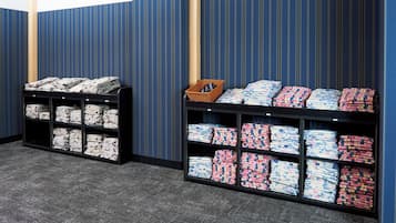 Una habitación con dos estanterías negras repletas de ropa de cama bien doblada.