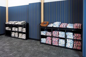 Una habitación con dos estanterías negras repletas de ropa de cama bien doblada.
