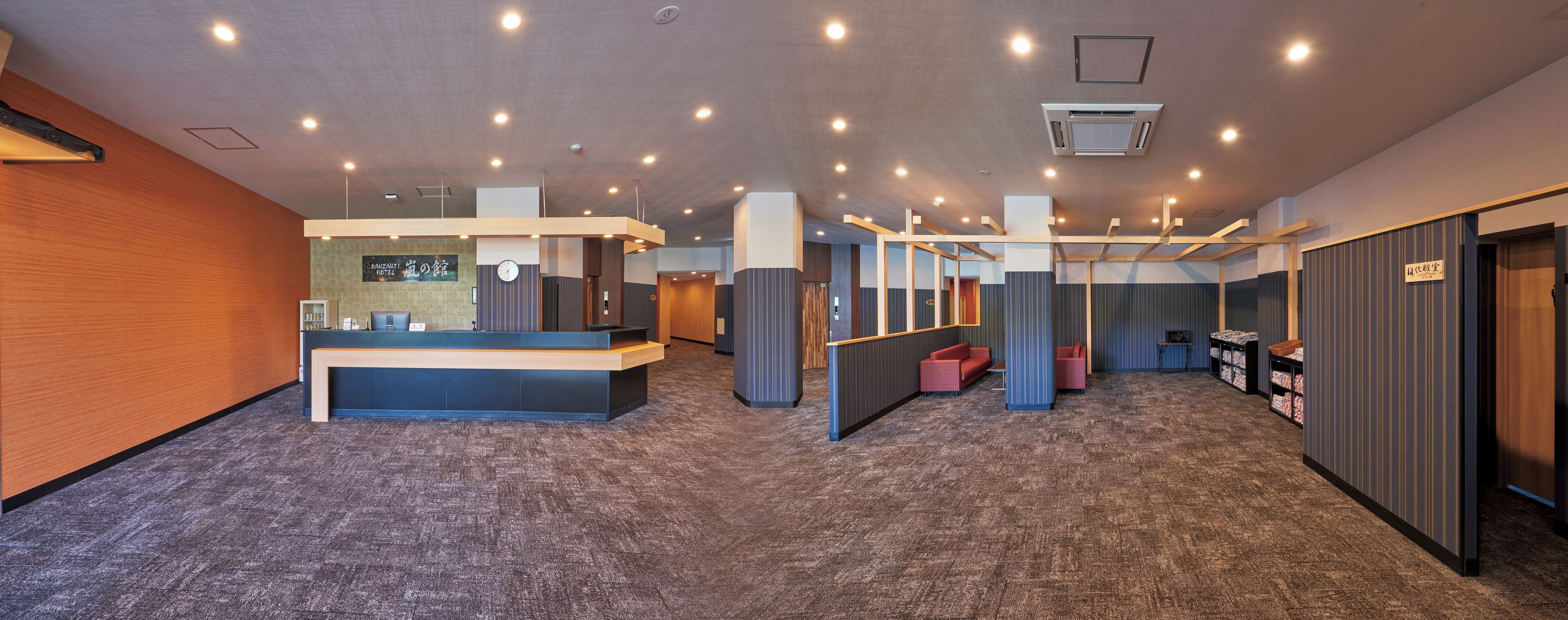 Een hotel receptie met een balie, zitplaatsen en een klok aan de muur.