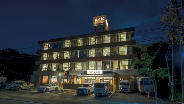 A multi-story hotel with a prominent sign, a parking lot with several cars, and a van. - Hamanako Kanzanji Onsen Arashi no Yakata (Hamamatsu)