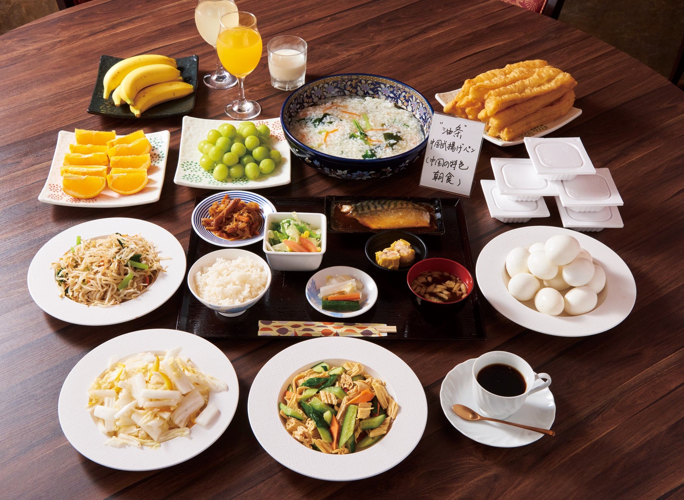 Ein Tisch mit verschiedenen Speisen, darunter Sushi, Reis und Gemüse, was auf eine japanische Mahlzeit hindeutet.