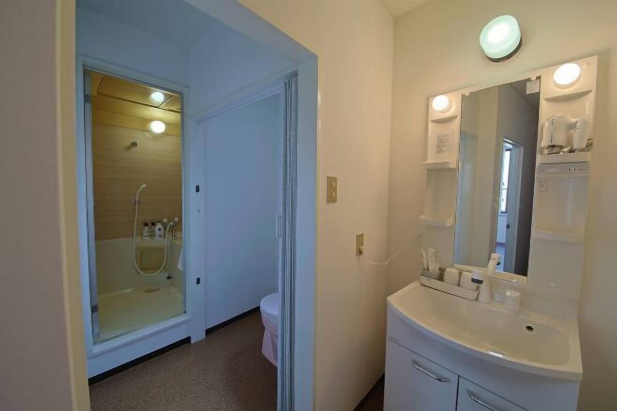 A bathroom with a glass-enclosed shower, a white sink with a mirror, and a toilet.