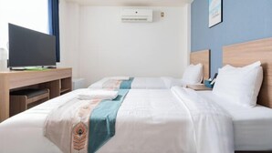 Habitación de hotel con dos camas, un escritorio con televisor, un equipo de aire acondicionado y un cuadro en la pared.