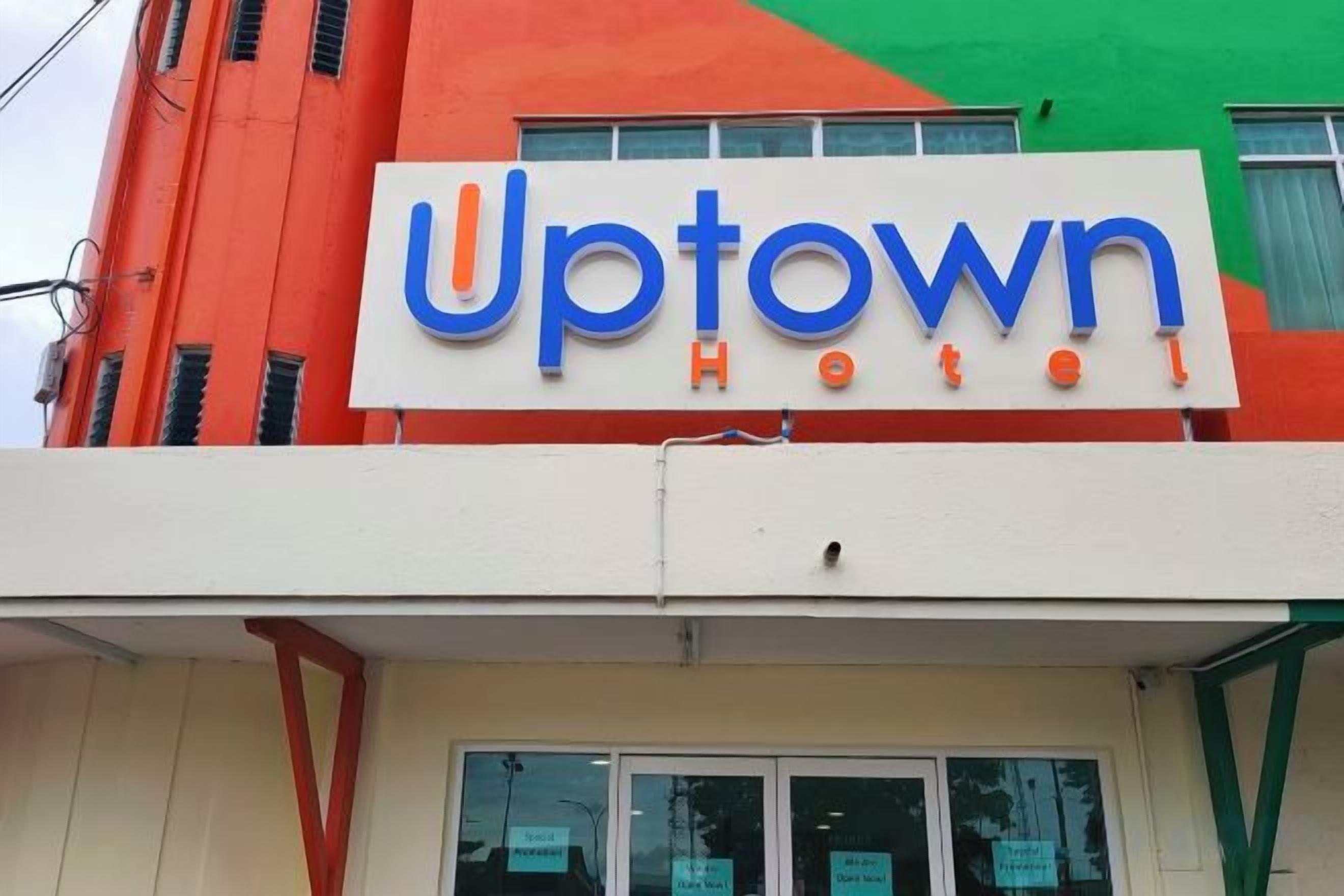 Et hotelskilt med navnet 'Uptown Hotel' i blå og orange bogstaver.