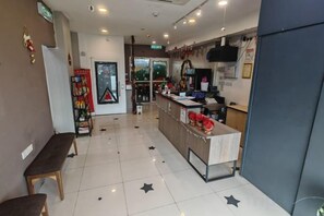 Un hall d’hôtel comprenant un comptoir d’accueil, un espace salon et un présentoir où sont exposés divers articles.