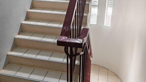 Una escalera con barandilla de madera y peldaños color beige.
