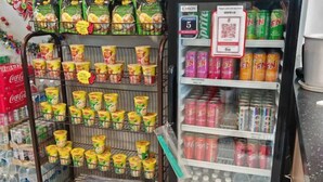 Mostrador refrigerado con diversas bebidas y aperitivos, incluyendo latas y botellas de agua.