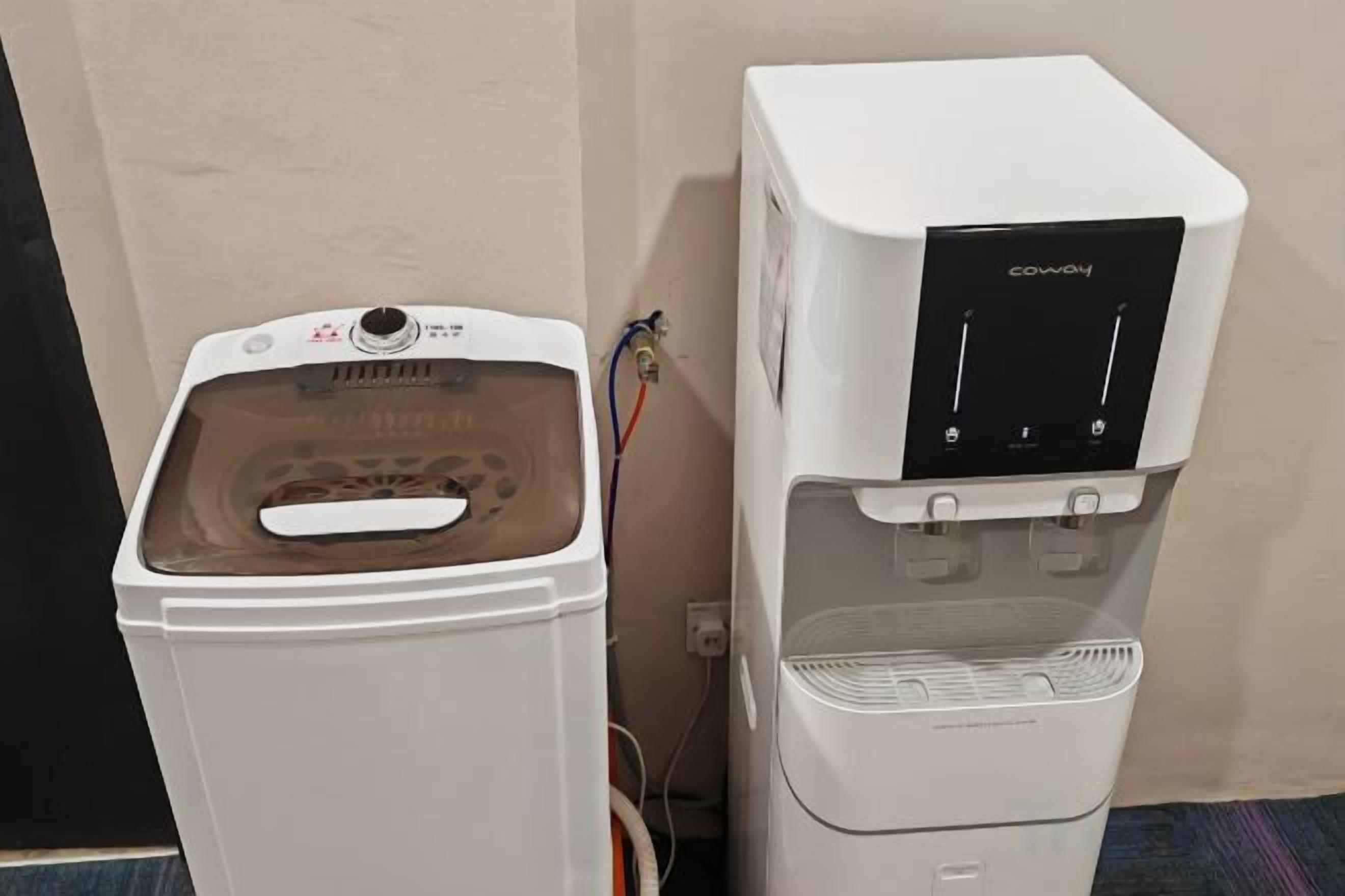 Un dispensador de agua y una lavadora uno al lado del otro.