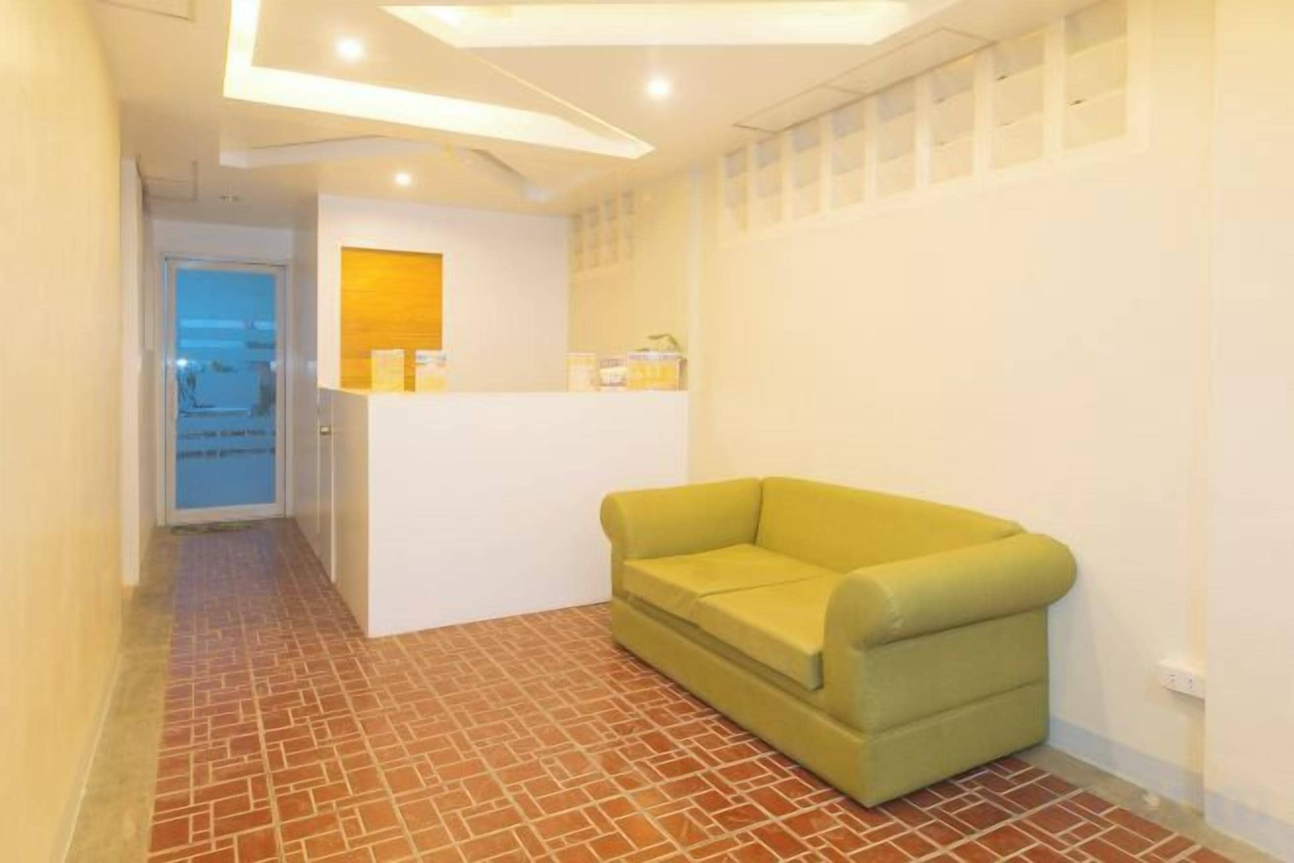 A reception area with a reception desk, a green sofa, and a tiled floor.