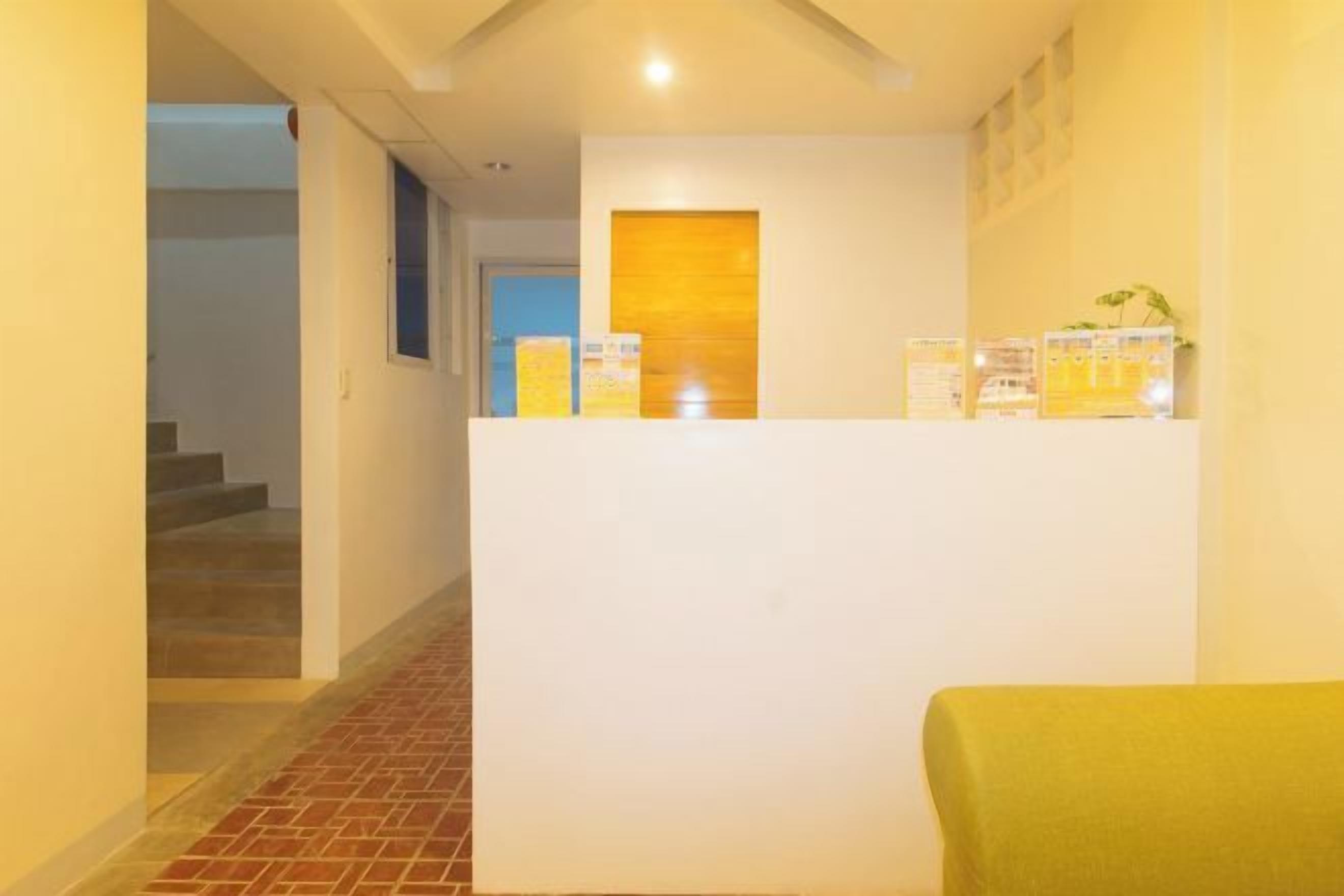 A reception area with a white reception desk, a staircase, and a yellow wall.