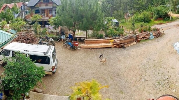 Ett bostadsområde med ett hus, parkerade fordon och utspridda byggmaterial.