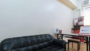 En svart lädersoffa i ett rum med ett träbord och stolar, en RedDoor-skylt och en RedDoor-logotyp på väggen.