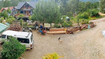 A rural setting with a house, parked vehicles, and construction materials.
