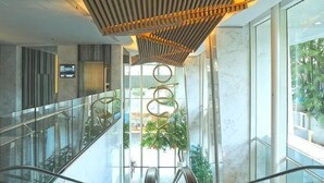 Een modern interieur met glazen balustrade, een centrale roltrap en een uniek plafondontwerp.