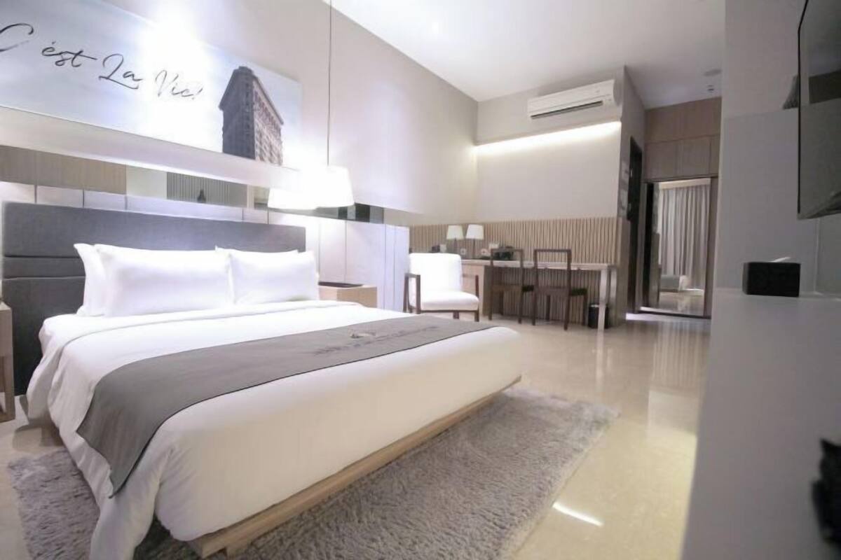 A modern hotel room with a large bed, a desk, and a chair.