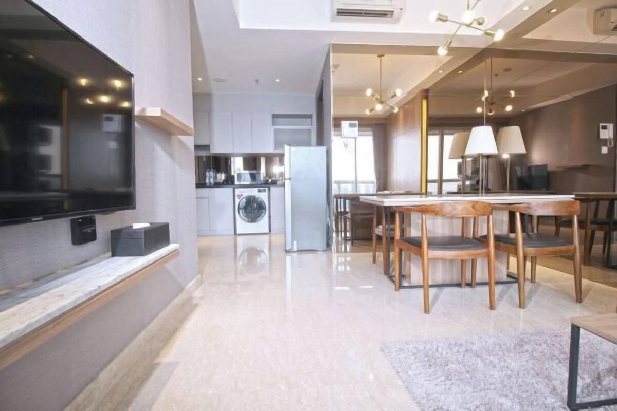 A modern kitchen with a built-in oven, a washing machine, and a dining area with a table and chairs.