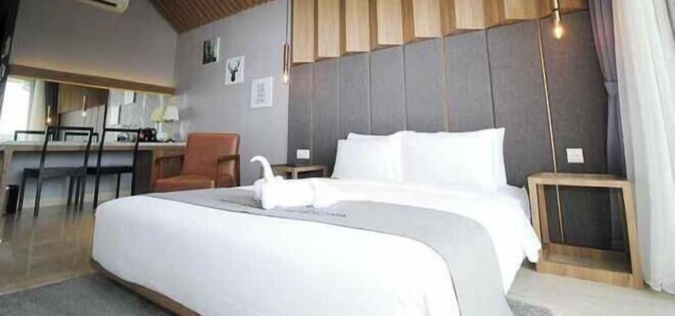 A hotel room with a large bed, a desk, a chair, and a small table.