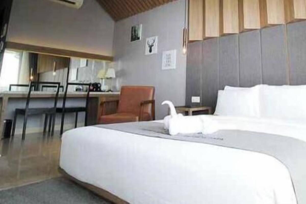 A hotel room with a large bed, a desk, a chair, and a small table.