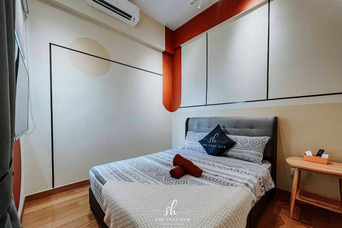 A modern bedroom with a bed, a small bedside table, and a wall-mounted air conditioner.