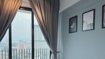 A room with a large window, curtains, and three framed pictures on the wall.