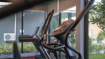 A stationary bike with a digital display, positioned near a window with a view of greenery outside.