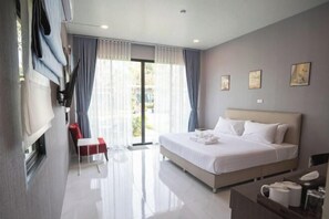 Quarto de hotel moderno com uma cama grande, uma escrivaninha e uma cadeira. Há cortinas nas janelas e obras de arte nas paredes.