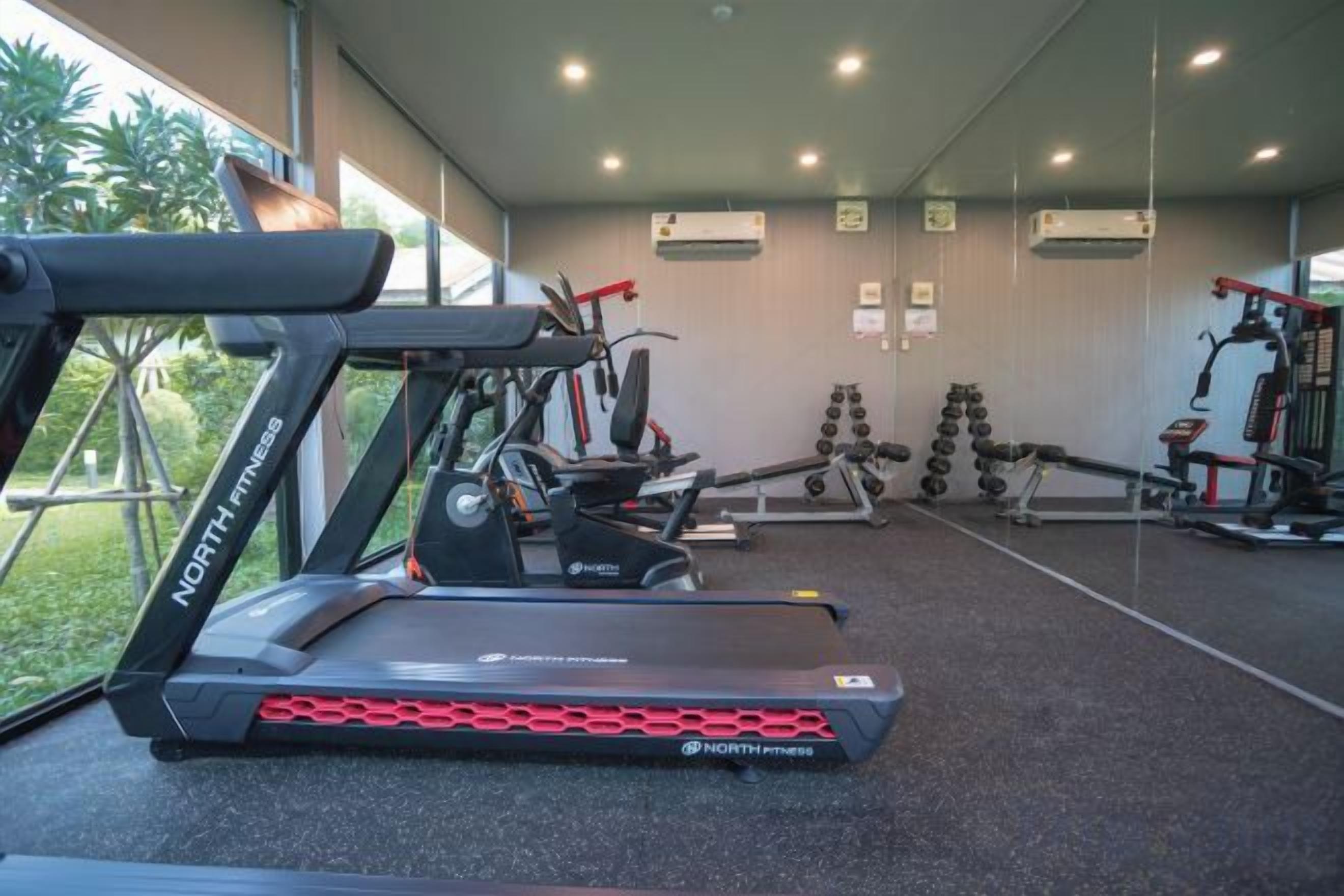 Un gimnasio con cintas de correr, pesas y equipamiento de ejercicio.