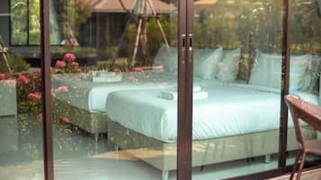 A bedroom with a glass wall, a bed, and a chair.
