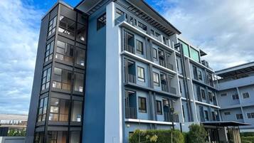 A multi-story building with a modern architectural design, featuring balconies and large windows.