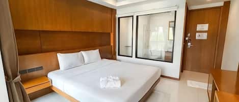 A modern hotel room with a large bed, a wooden headboard, a bedside table, and a large mirror.